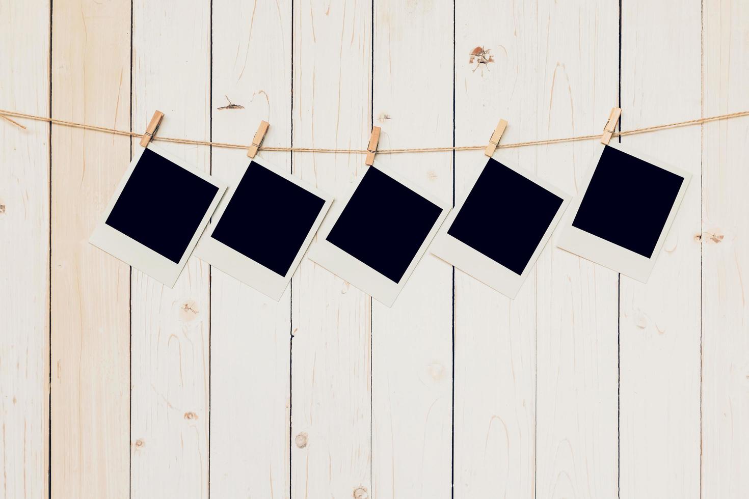 Five blank photo frame hanging on white wood background with space.