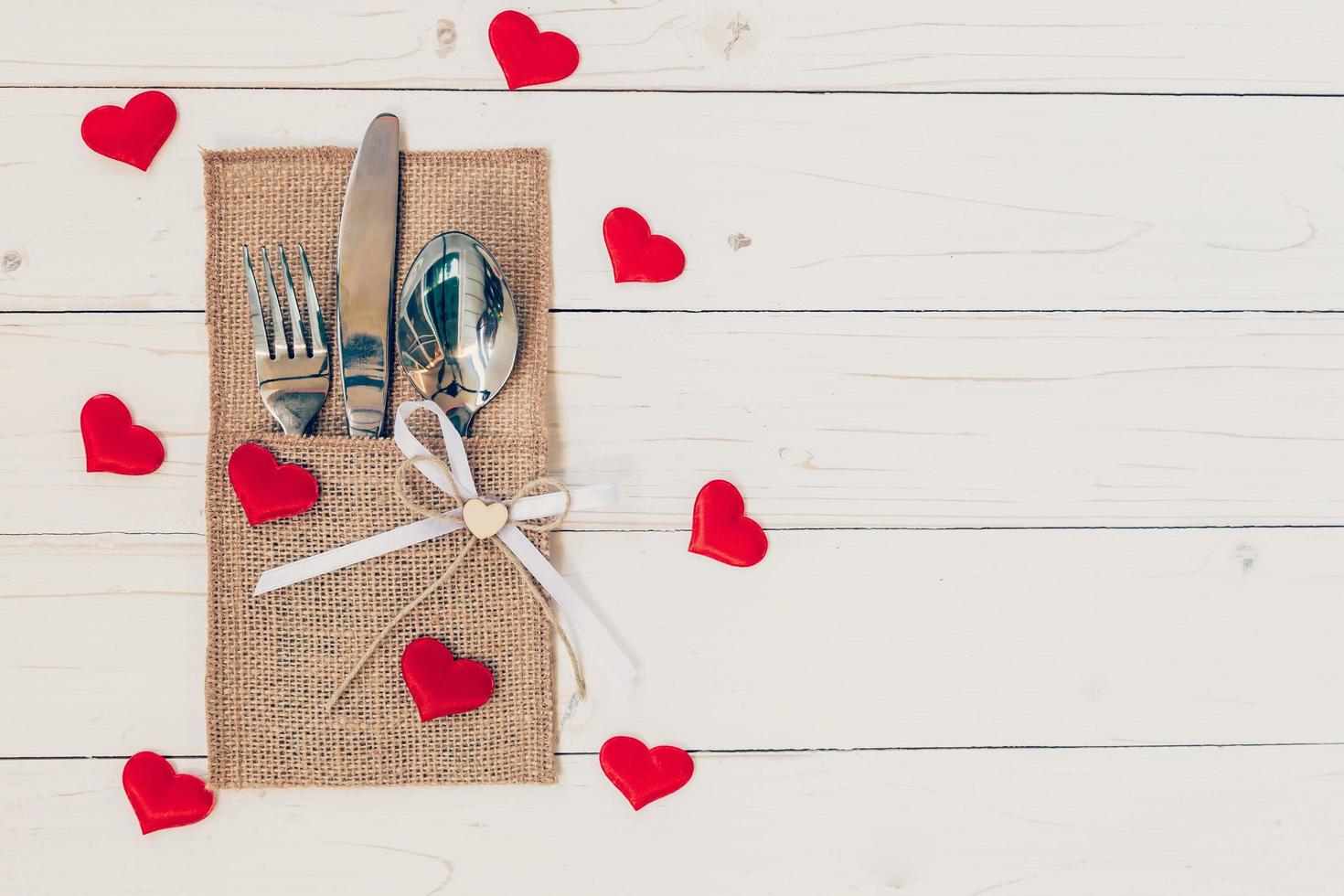 Table set for celebration Valentine's Day. Wooden table place setting and silverware with red heart for Valentine day. photo