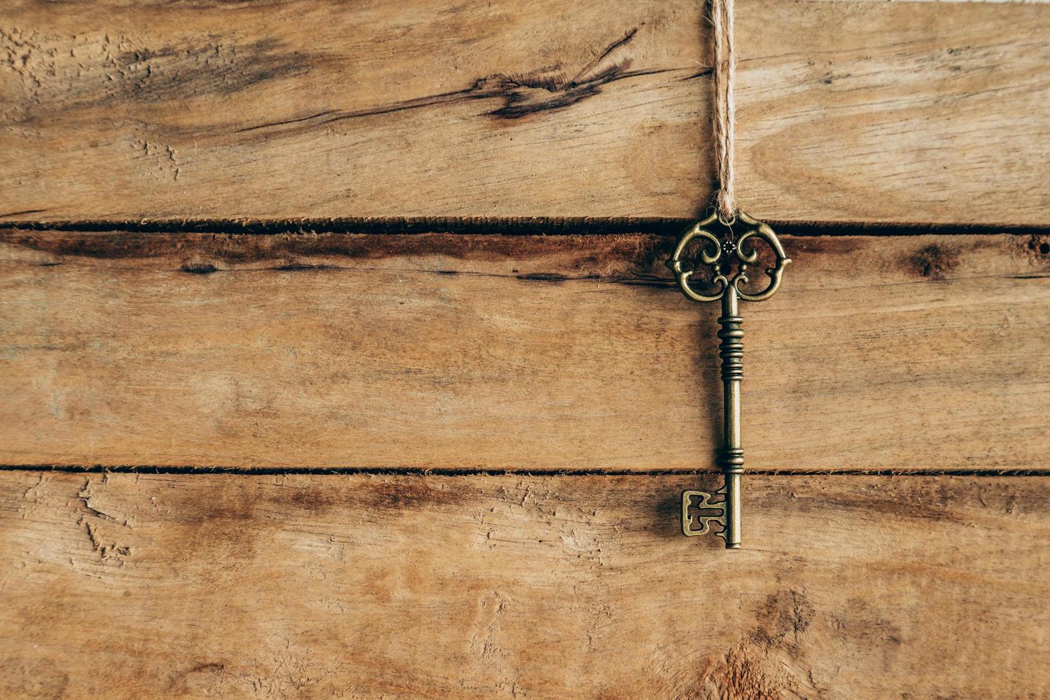 Old key hanging on brown wood with space. photo