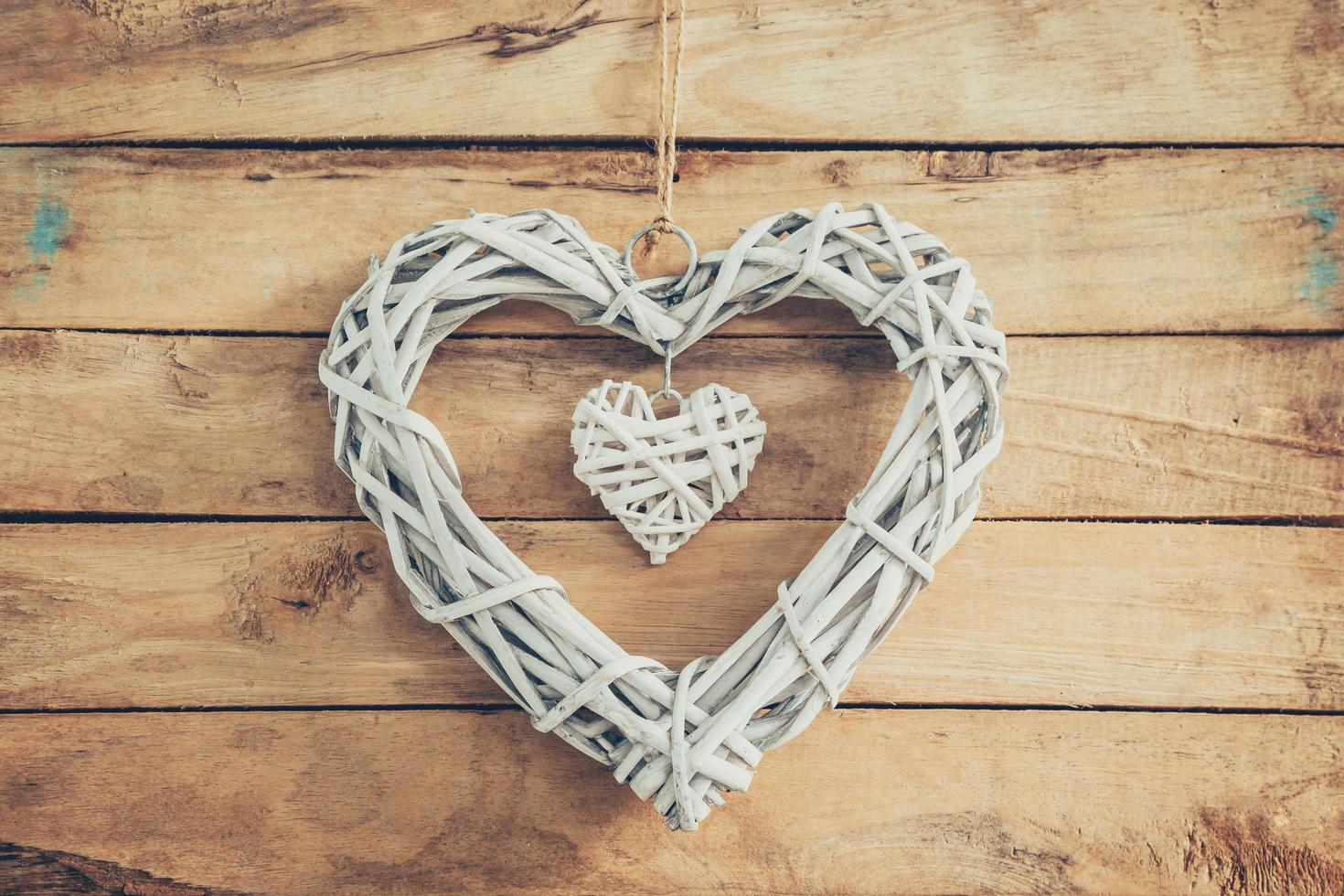 Two wooden rustic decorative hearts hanging on vintage wooden background with space. photo