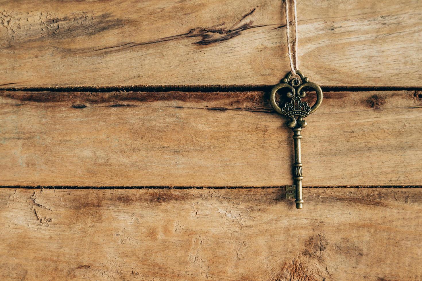 Old key hanging on brown wood with space. photo