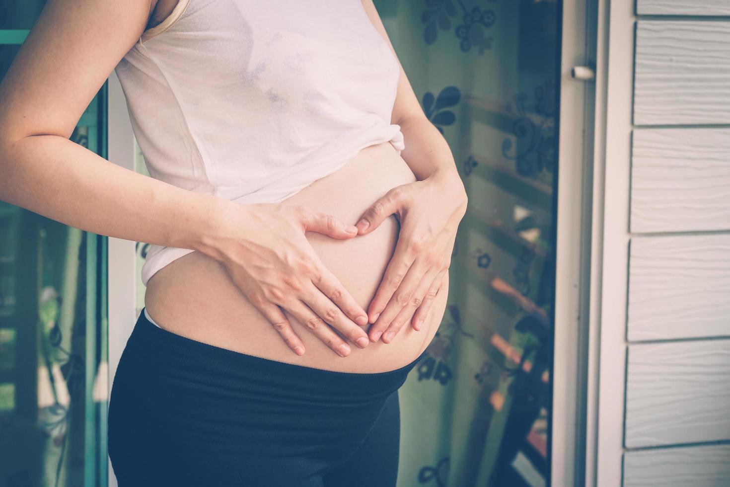 embarazada mujer participación mano corazón forma para bebé en su barriguita foto