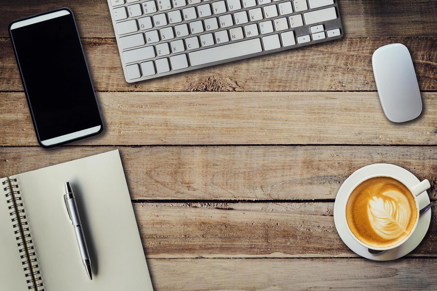 Office table with coffee cup, computer, phone, notebook and pen. View from above with copy space photo