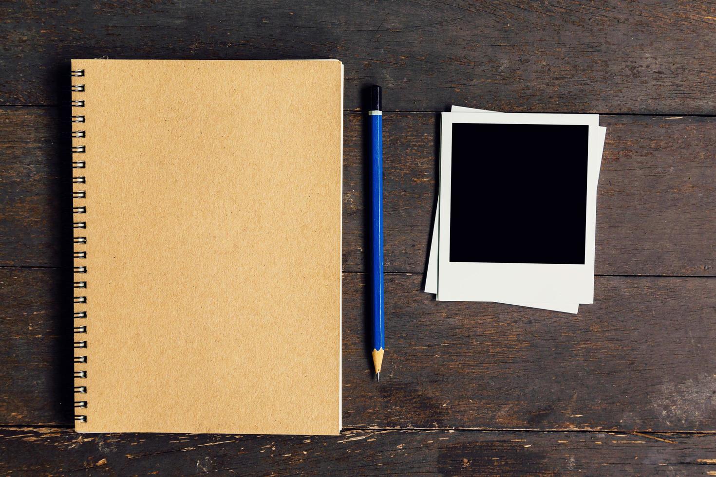 brown book and pencil with frame photo on wood table background with space