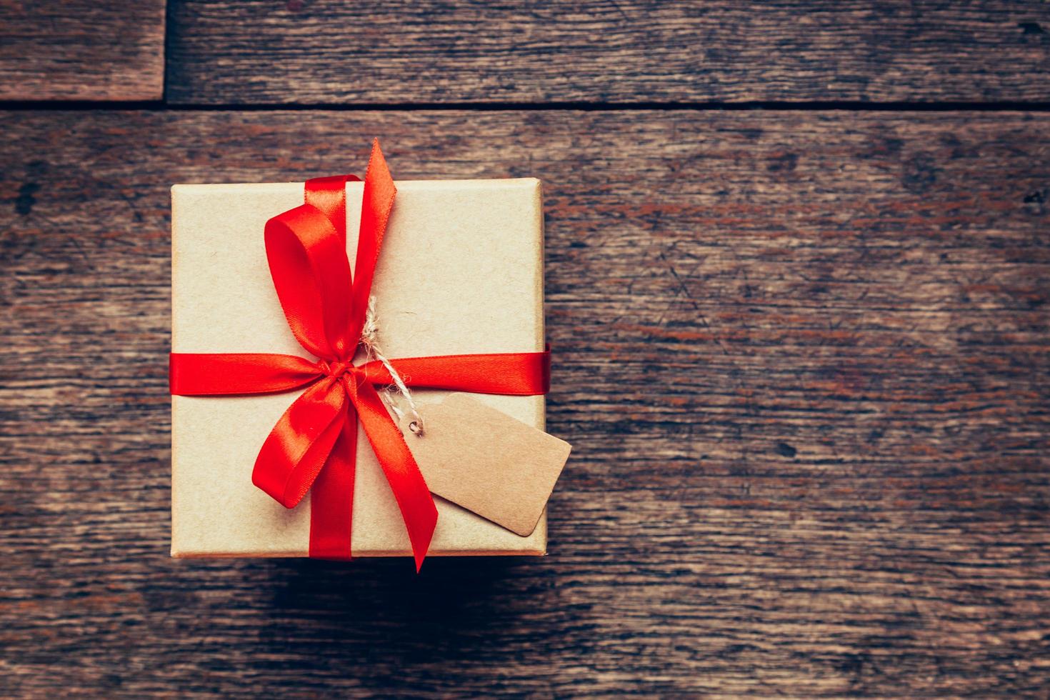 View above brown gift box and red ribbon with tag on wood background with space. photo