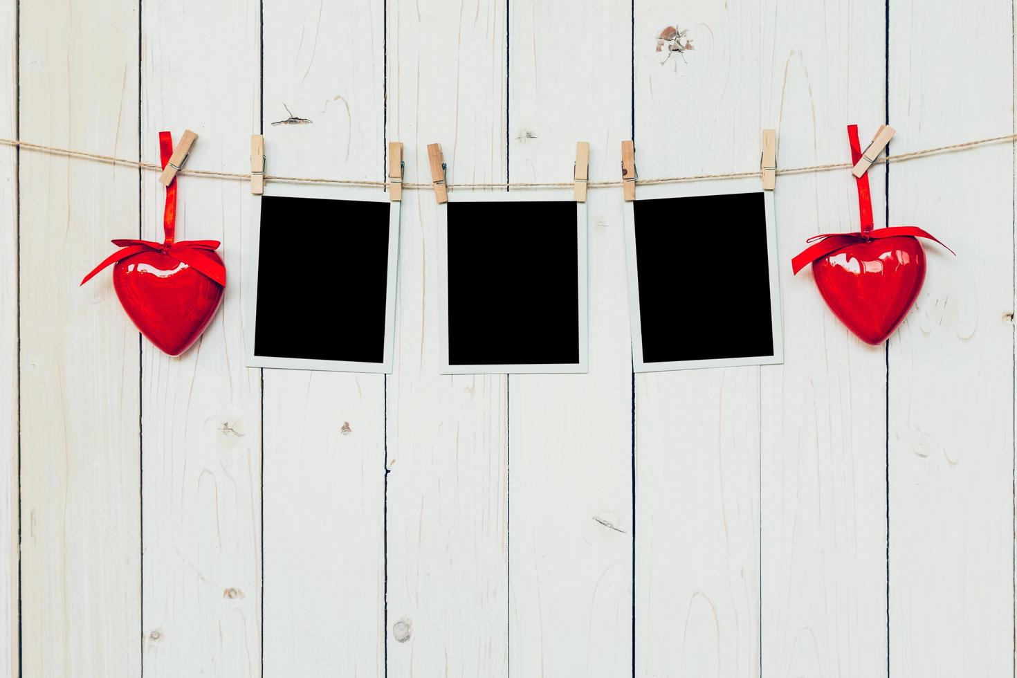 three photo frame blank and red heart hanging on white wood background with space