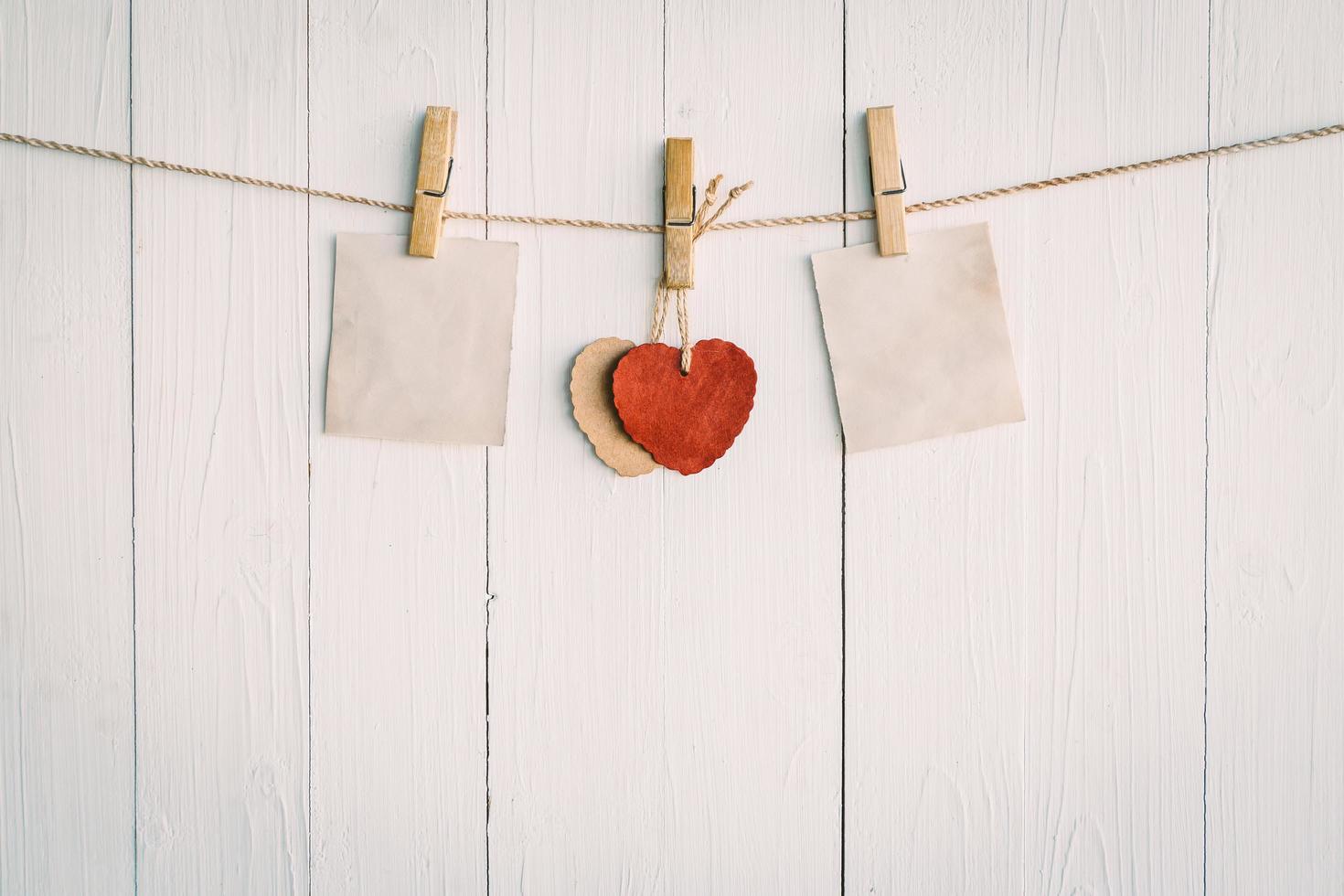 Two blank old paper and red heart hanging. On white wooden background with vintage style. photo