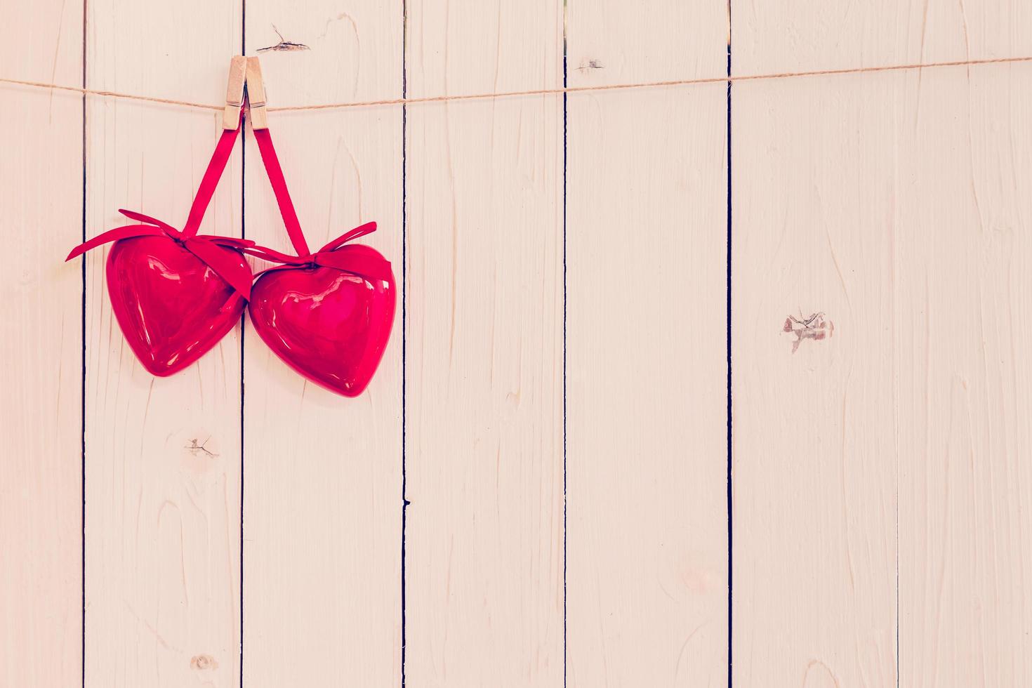 Two red heart hanging on white wood background with space. photo