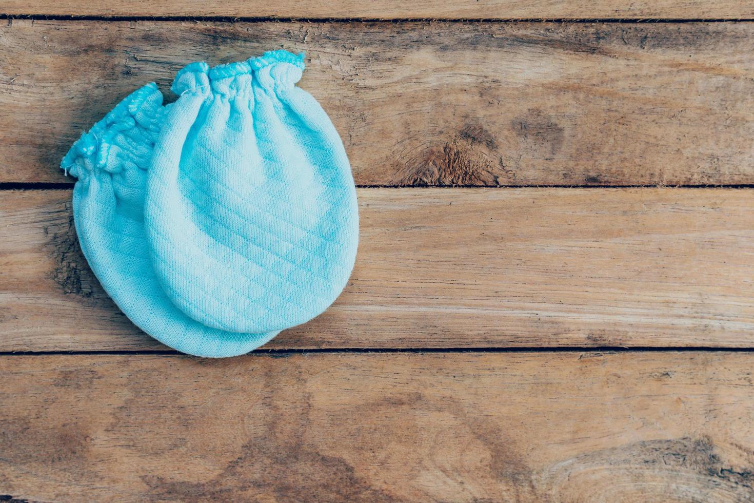 baby gloves on wooden background with space photo