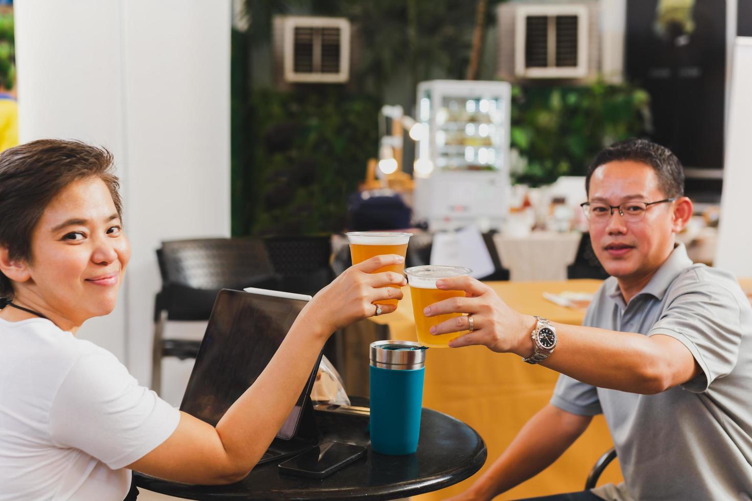 Happy couple hands holding glasses of beer toasting. photo