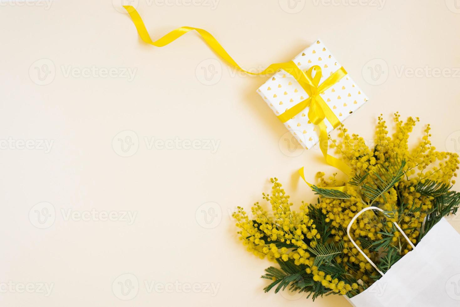 hermosas flores con paquete y composición actual. ramas flores mimosa sobre fondo blanco. día de san valentín, pascua, cumpleaños, día de la madre. plano plano, vista superior, espacio de copia. venta de primavera foto