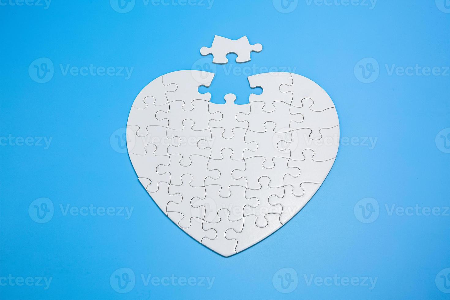 White jigsaw puzzle on a blue background. Completing final task, missing jigsaw puzzle pieces and business concept with a puzzle piece missing. photo