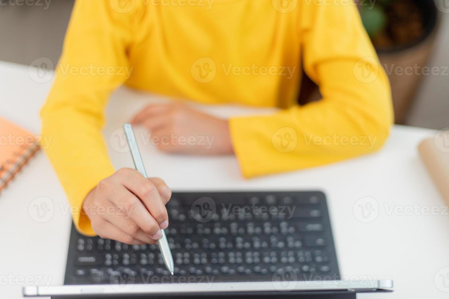 Asian schoolgirl doing her homework with digital tablet at home. Children use gadgets to study. Education and distance learning for kids. Homeschooling during quarantine. Stay at home photo