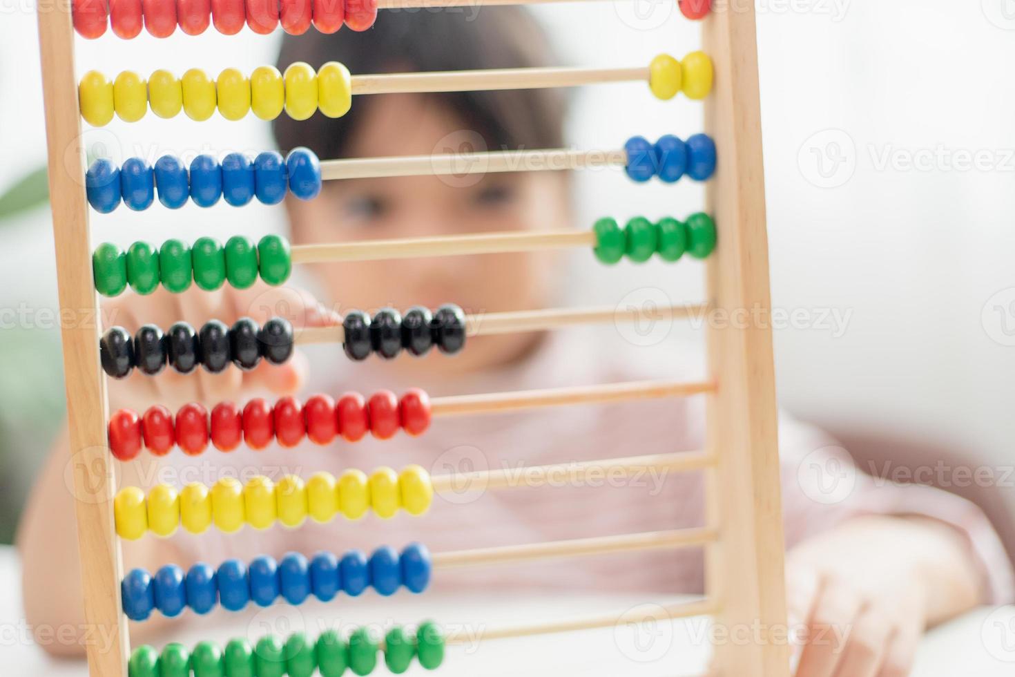 una joven asiática linda está usando el ábaco con cuentas de colores para aprender a contar en casa foto