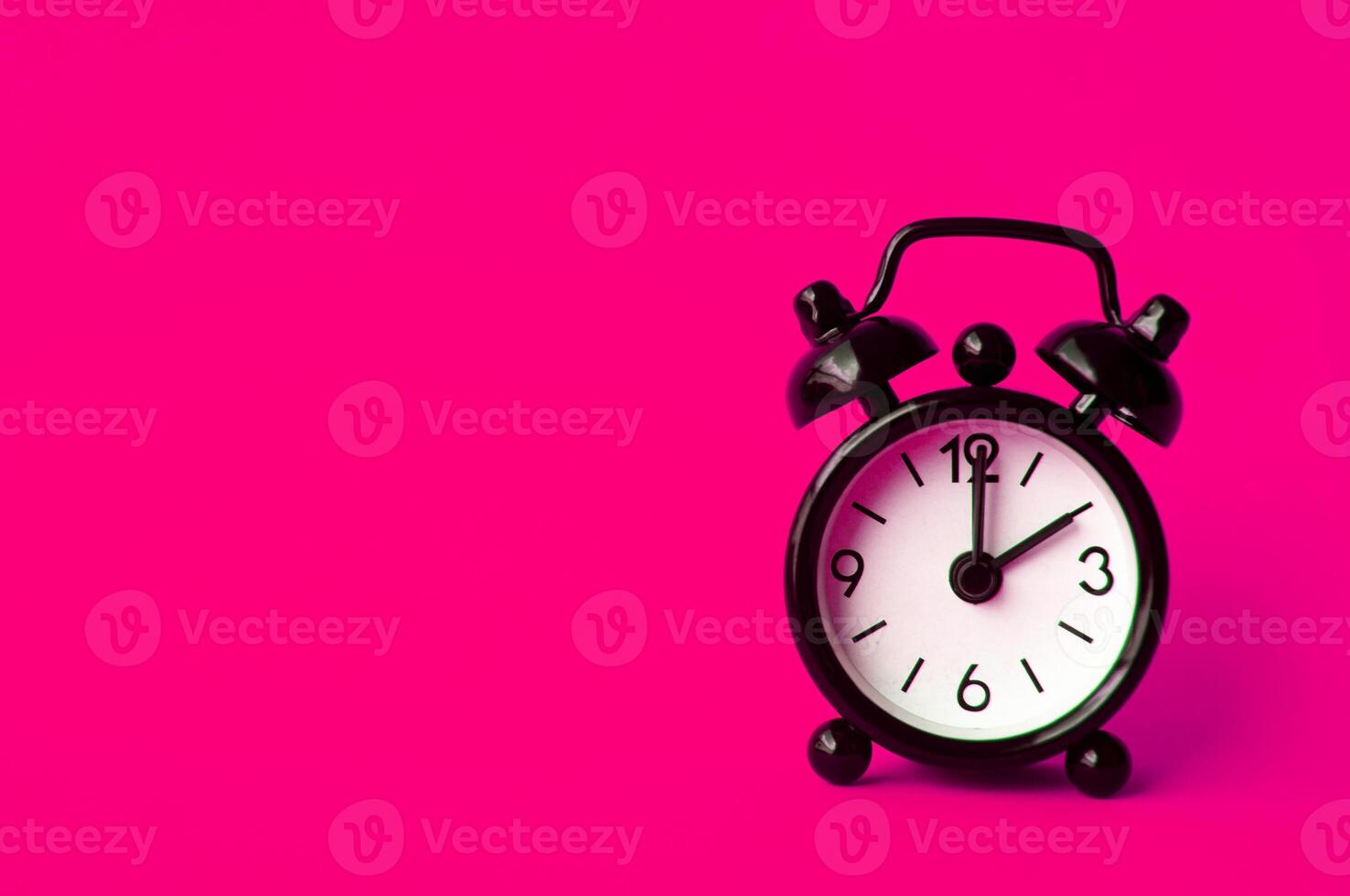 Alarm clock pointing at 2 am or pm with customizable space for text or ideas. Copy space with pink background photo