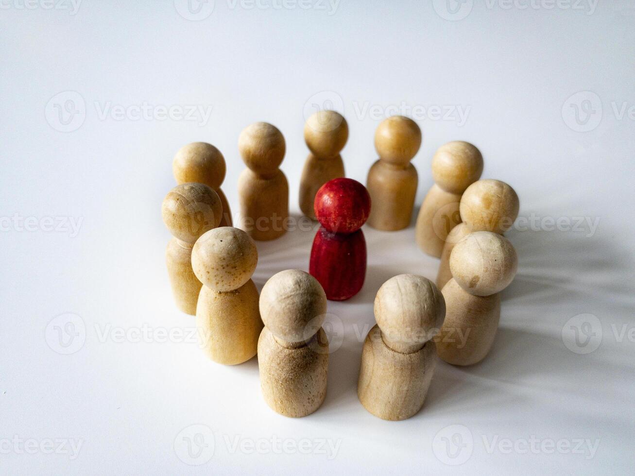 Red wooden doll figure surrounded by other doll figure on white background. Harassment and bully concept. Copy space. photo