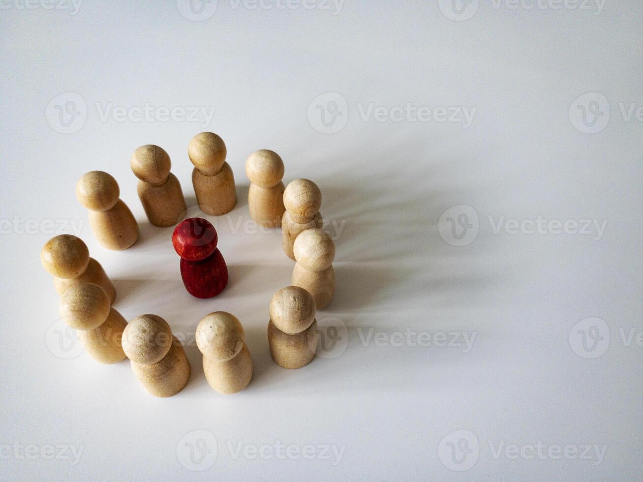 Red wooden doll figure surrounded by other doll figure on white background. Harassment and bully concept. Copy space. photo