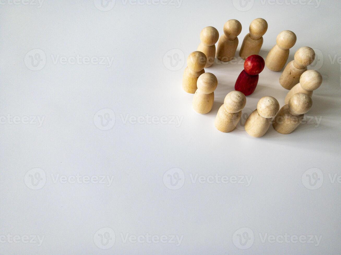 Red wooden doll figure surrounded by other doll figure on white background. Harassment and bully concept. Copy space. photo