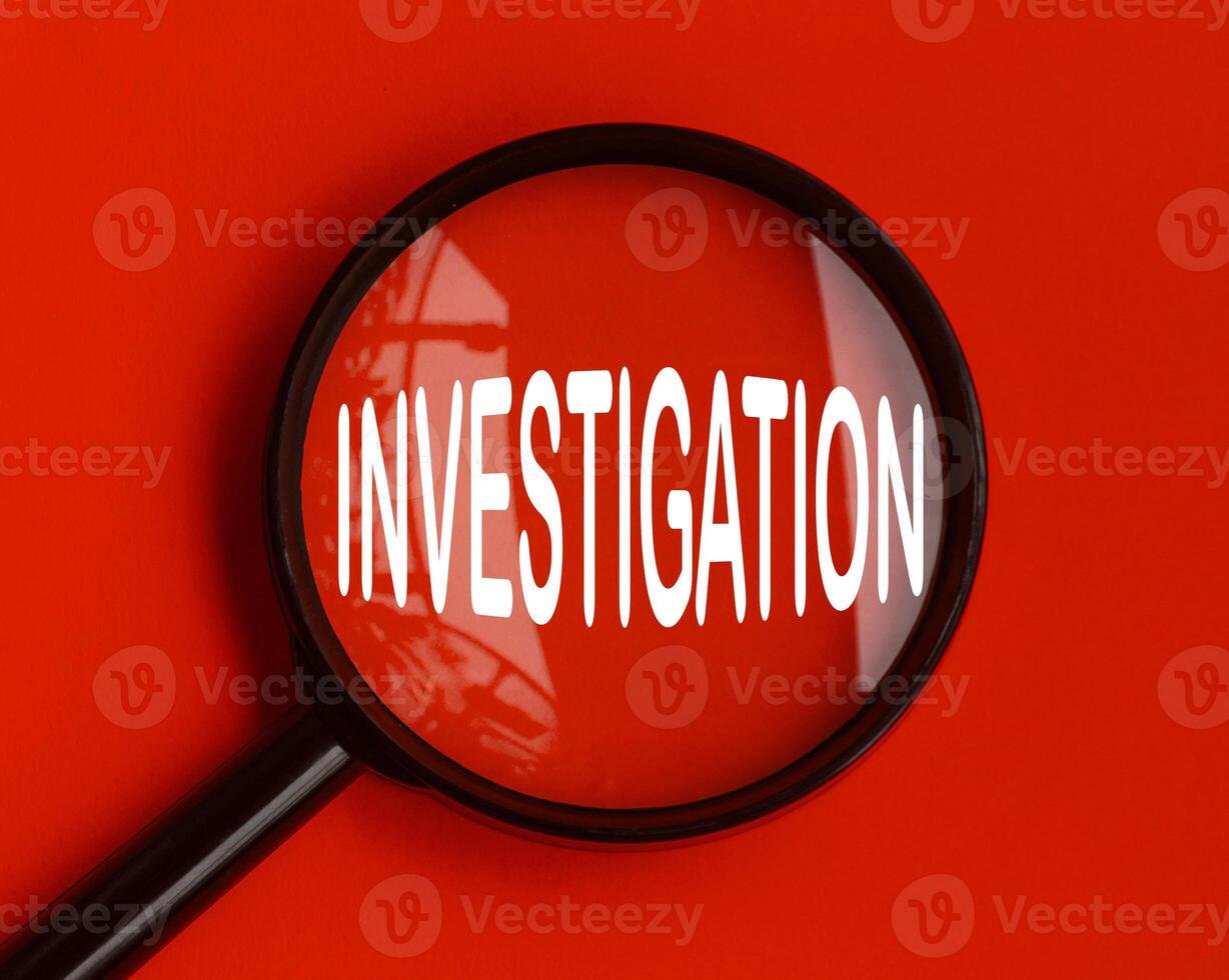 Investigation text on red cover with magnifying glass. Scamming and fraud concept photo