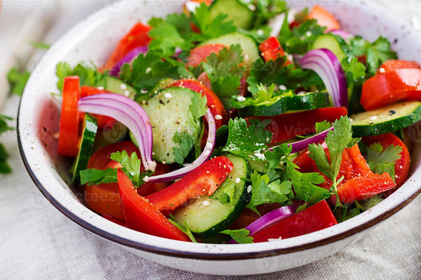 tomate y Pepino ensalada con rojo cebolla, pimenton, negro pimienta y perejil. vegano alimento. dieta menú. foto