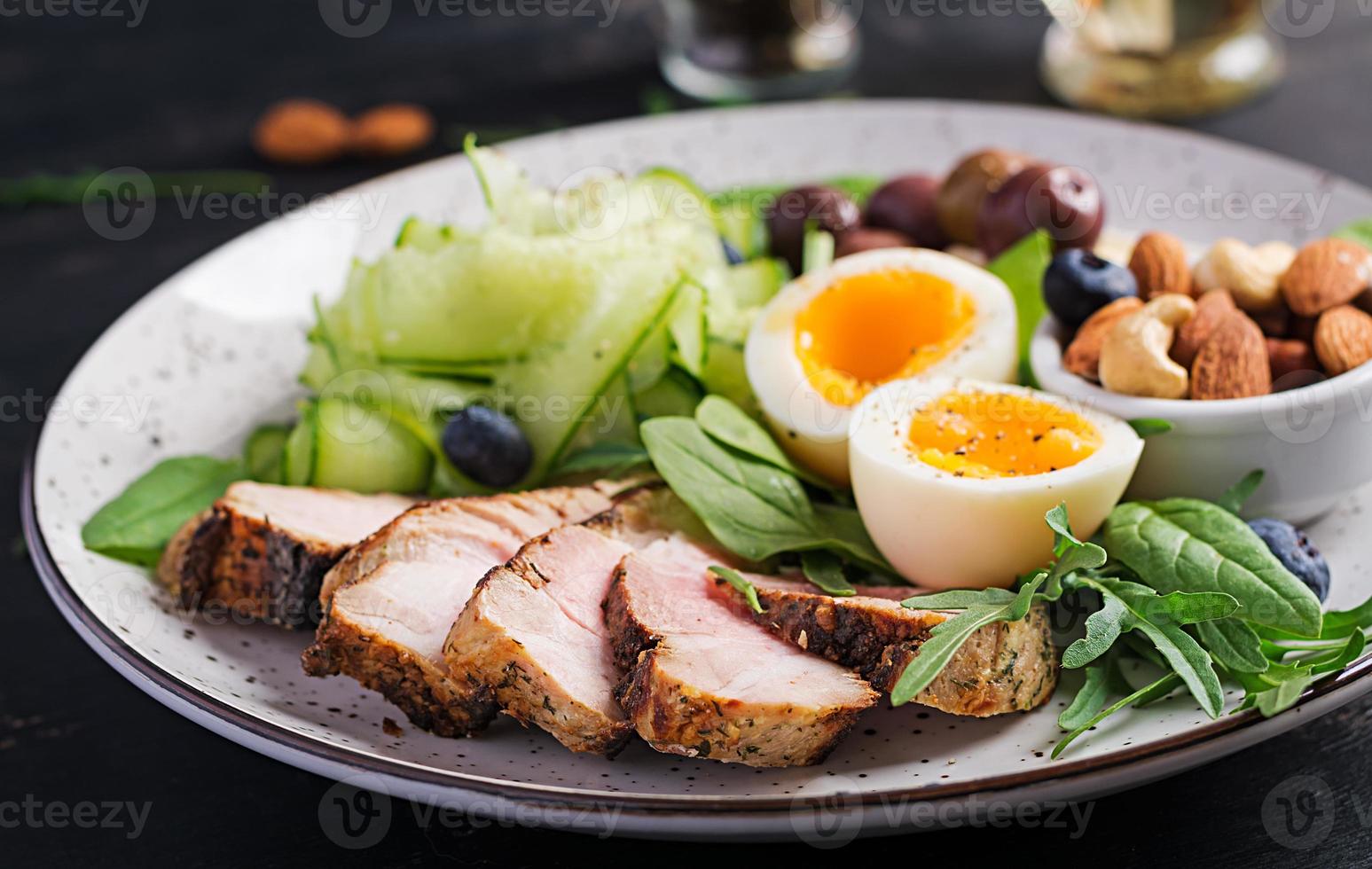 Ketogenic diet. Keto brunch. Boiled egg, pork steak and olives, cucumber, spinach, brie cheese, nuts and blueberry. photo