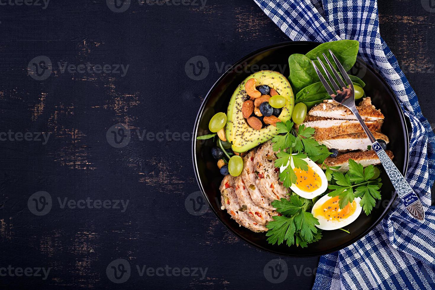 Ketogenic diet. Buddha bowl dish with meatloaf, chicken meat, avocado, berries and nuts. Detox and healthy concept. Keto food. Overhead, top view, flat lay photo