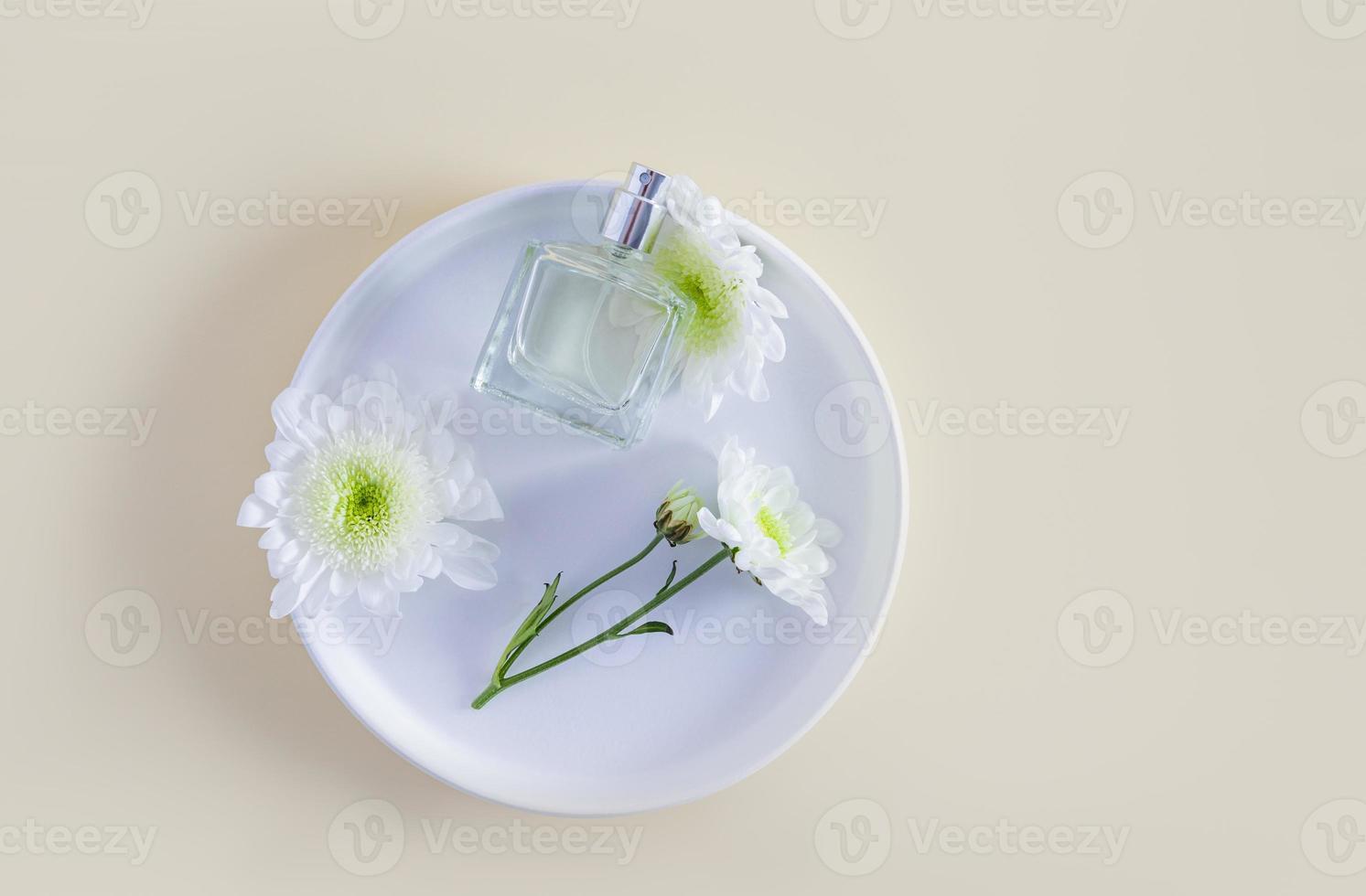 a chic bottle with a cosmetic product or spray on a white ceramic plate and flowers. top view. pastel background. a copy space. feminine essence. photo