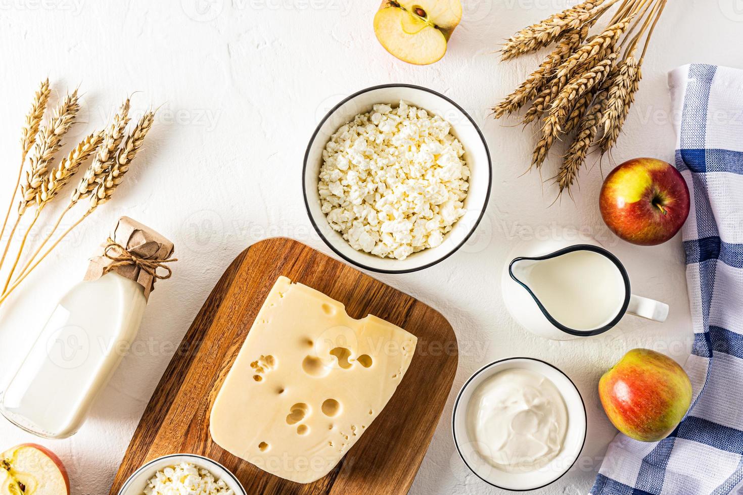 festivo antecedentes para el judío primavera fiesta de shavuot. un montón de lechería productos, manzanas y orejas de un pan. parte superior vista. plano poner. foto