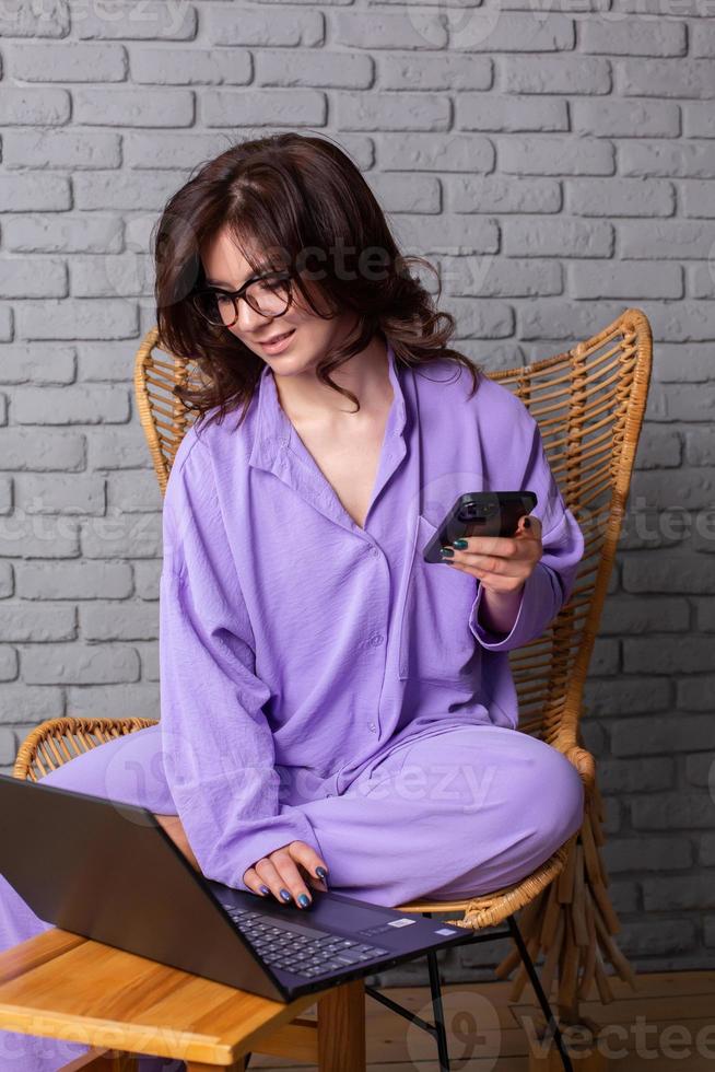 Beautiful businesswoman working on a laptop in a chair near the window. Female freelancer connecting to internet via computer. Blogger or journalist writing new article. photo
