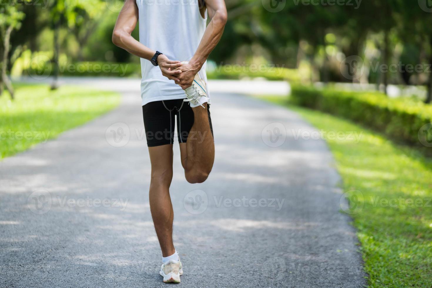 Athletes sport man runner wearing white sportswear to stretching foot and legs and warm up before practicing on a running track at a stadium park. Runner sport concept. photo