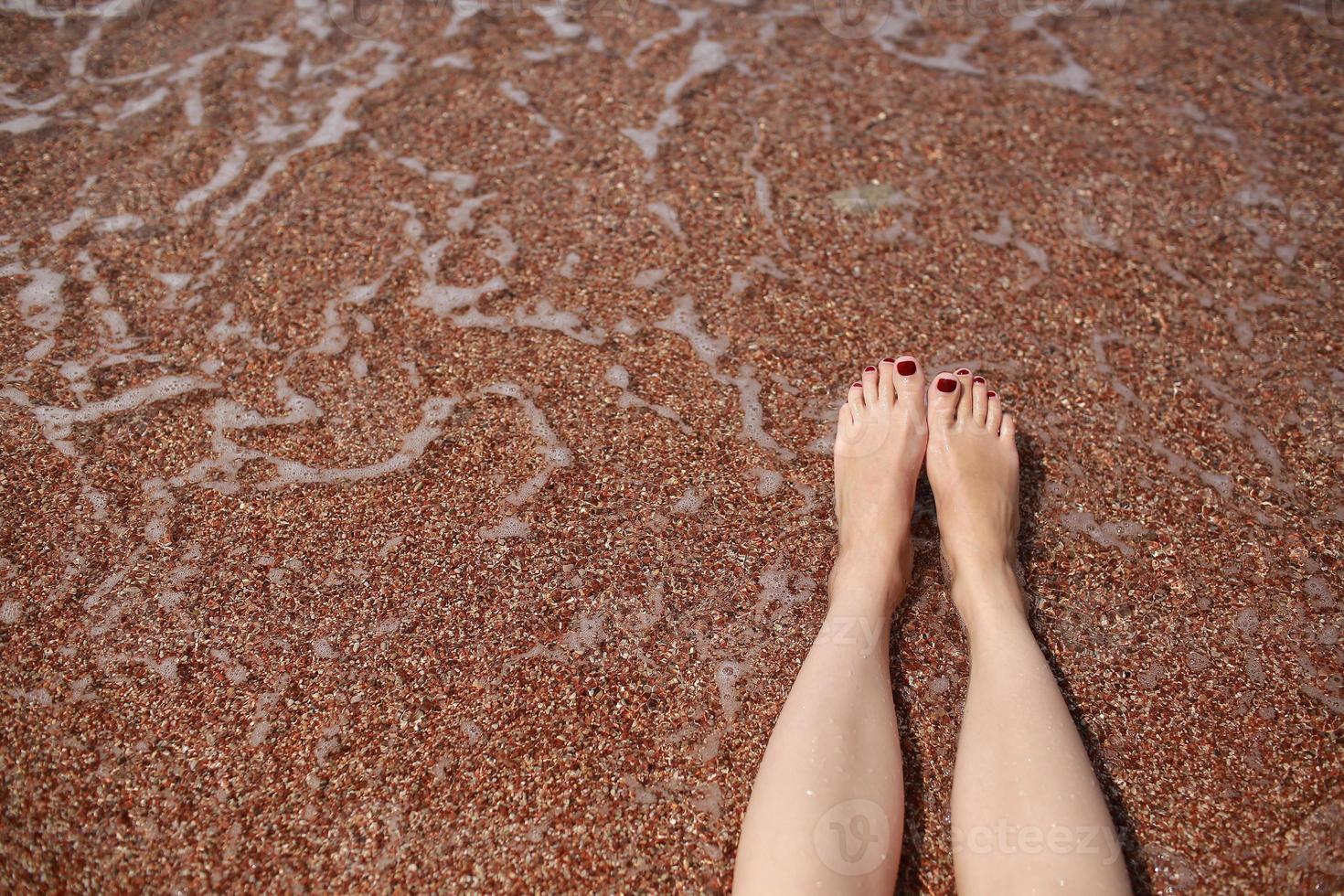 Travel concept Woman's legs on beautiful tropical beach with pebble