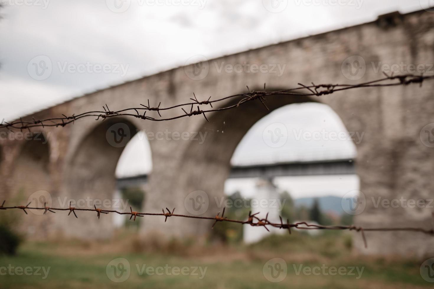 metal rusty fence on the background of the Old Railway Bridge, the old viaduct of Vorokhta, Ukraine. Carpathians, wild mountain landscape photo