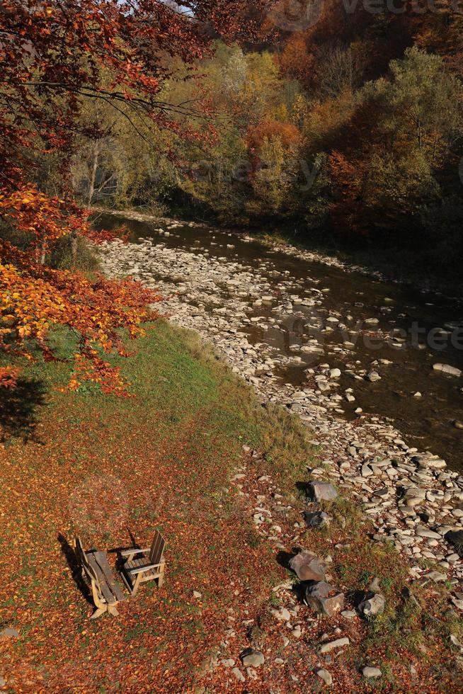 Beautiful nature landscape. View of mountain wild river in Carpathian mountains during sunny autumn day, Ukraine. a place for relaxation, a table and a bench in nature photo