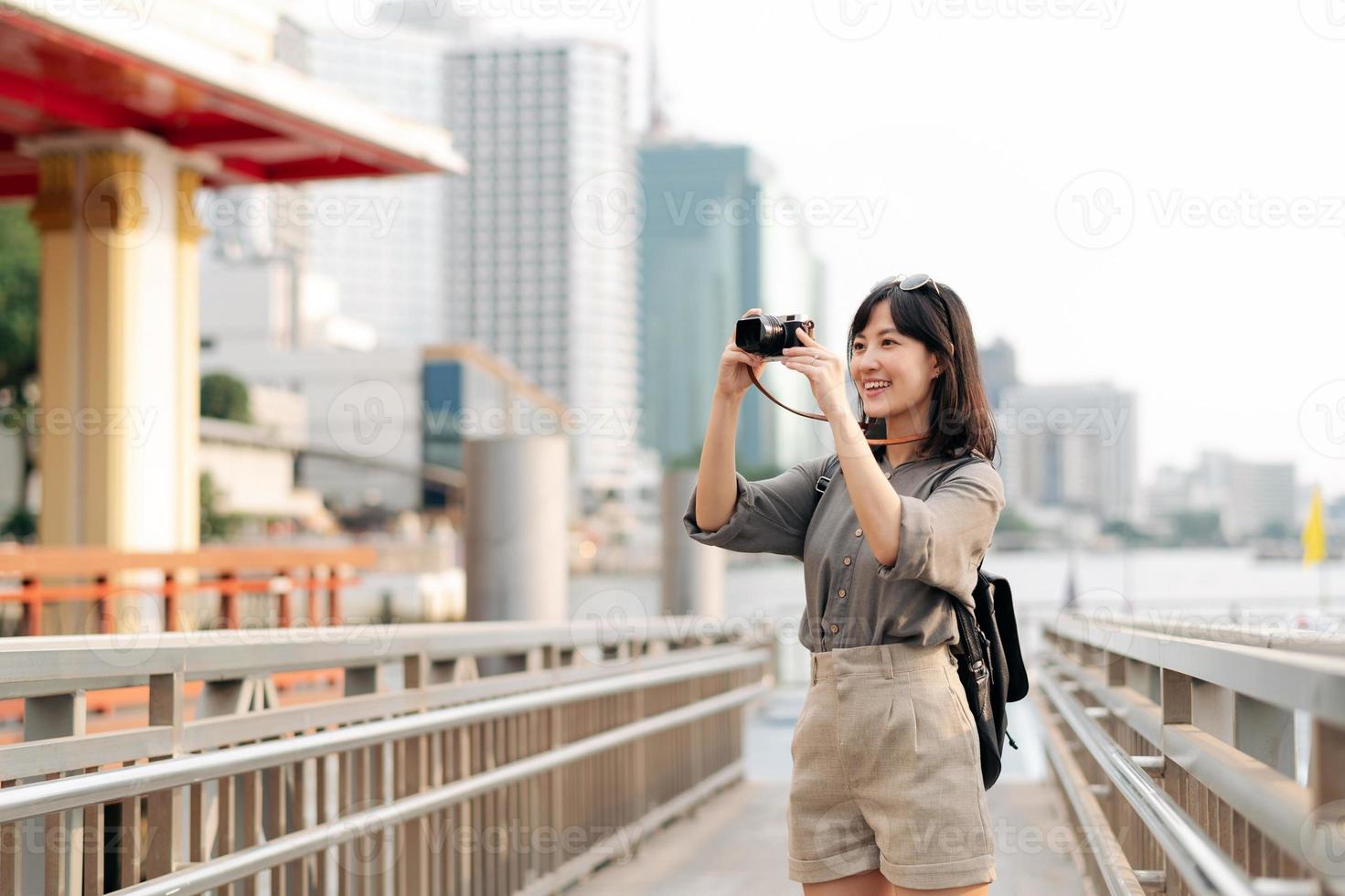 joven asiático mujer mochila viajero utilizando un cámara en Rápido barco muelle en chao phraya río en bangkok foto