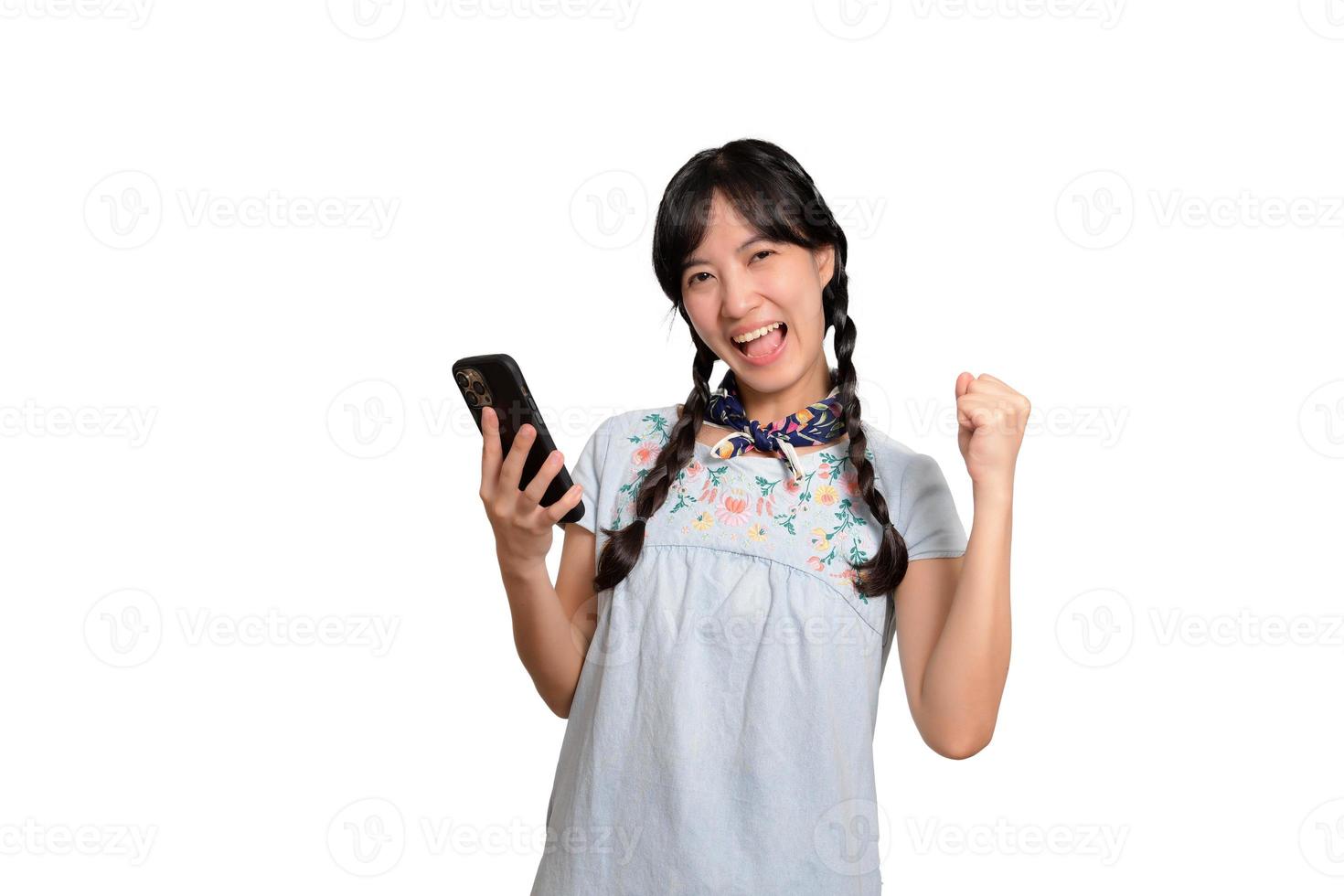 Portrait of happy beautiful young asian woman in denim dress using a smartphone on white background. studio shot photo