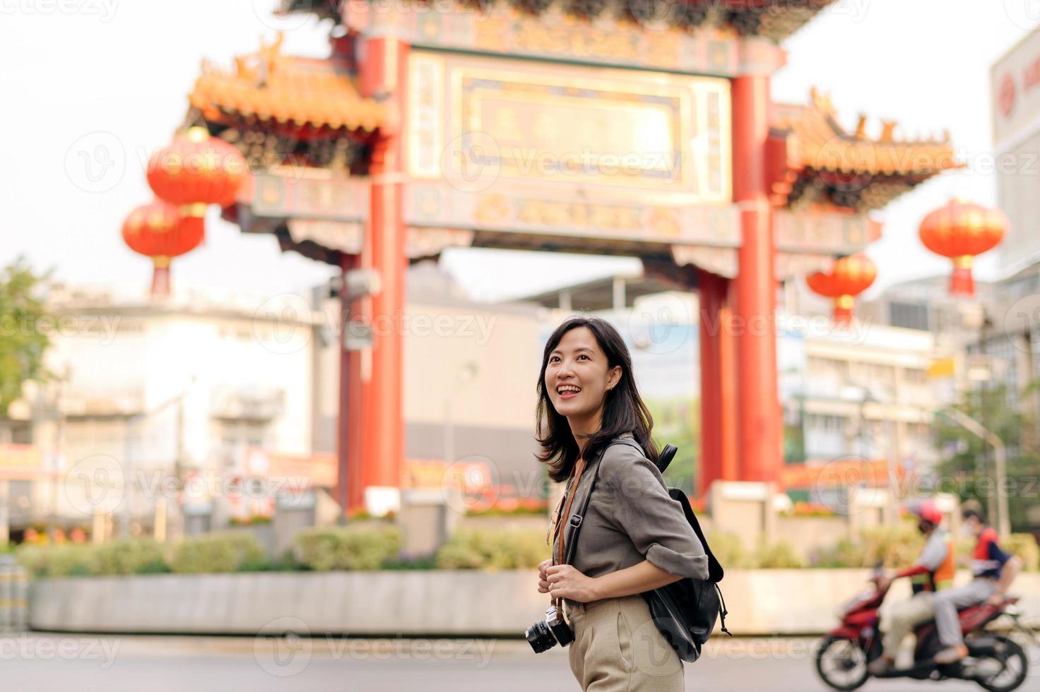 Young Asian woman backpack traveler enjoying China town street food market in Bangkok, Thailand. Traveler checking out side streets. photo