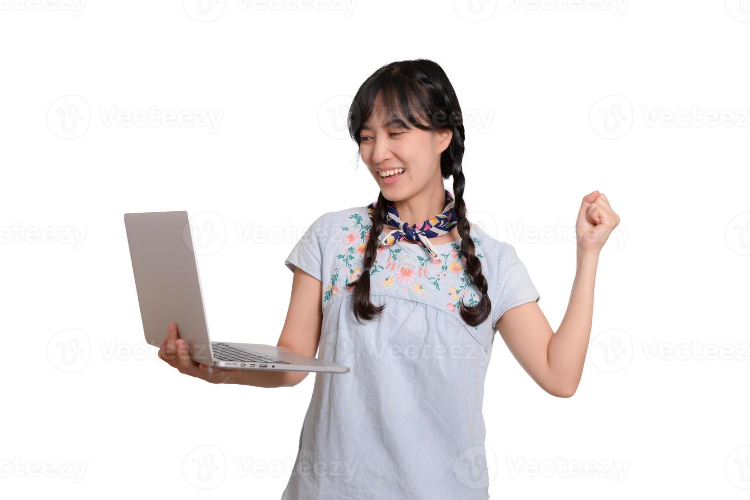 Portrait of beautiful happy young freelance asian woman in denim dress using laptop work with success on white background photo