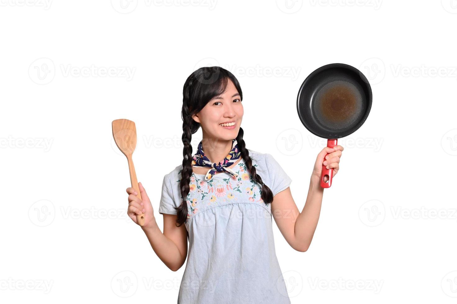 Portrait of beautiful young asian woman wear denim dress with black pan and spatula on white isolated background photo