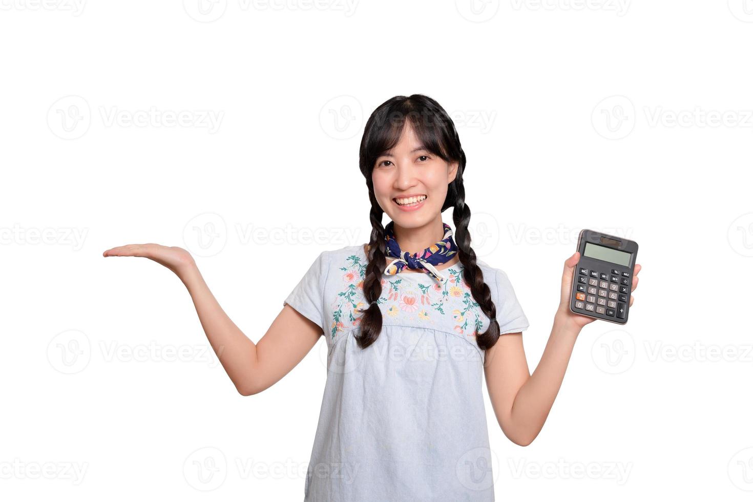 retrato de una hermosa joven asiática vestida de mezclilla sosteniendo una calculadora de fondo blanco. concepto de compras en línea de negocios. foto