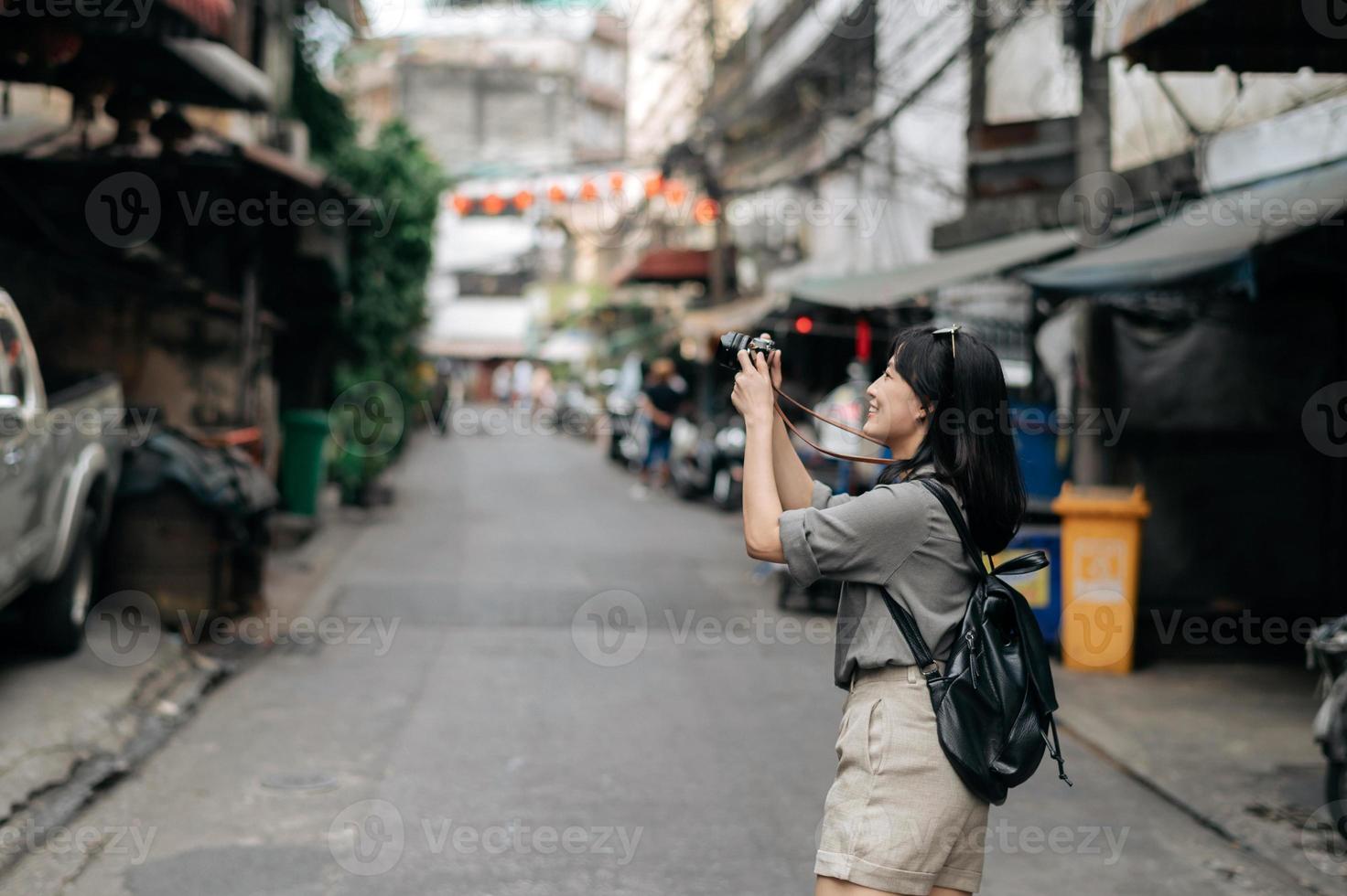 Young Asian woman backpack traveler using digital compact camera, enjoying street cultural local place and smile. photo