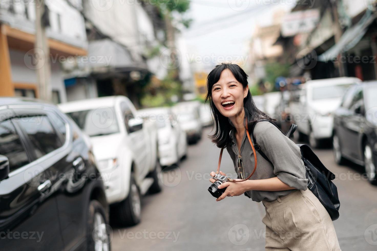 Young Asian woman backpack traveler using digital compact camera, enjoying street cultural local place and smile. photo