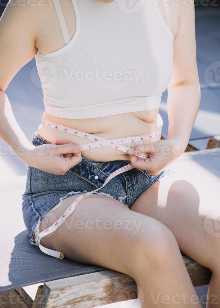 fat woman, fat belly, chubby, obese woman hand holding excessive belly fat with measure tape, woman diet lifestyle concept photo