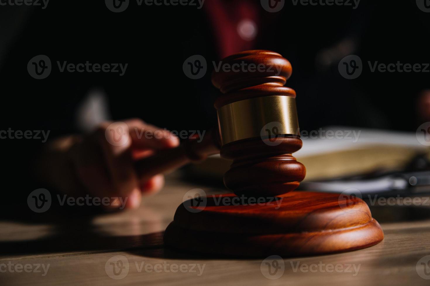 concepto de justicia y derecho. juez masculino en una sala de audiencias con el mazo, trabajando con computadora y teclado de acoplamiento, anteojos, en la mesa a la luz de la mañana foto