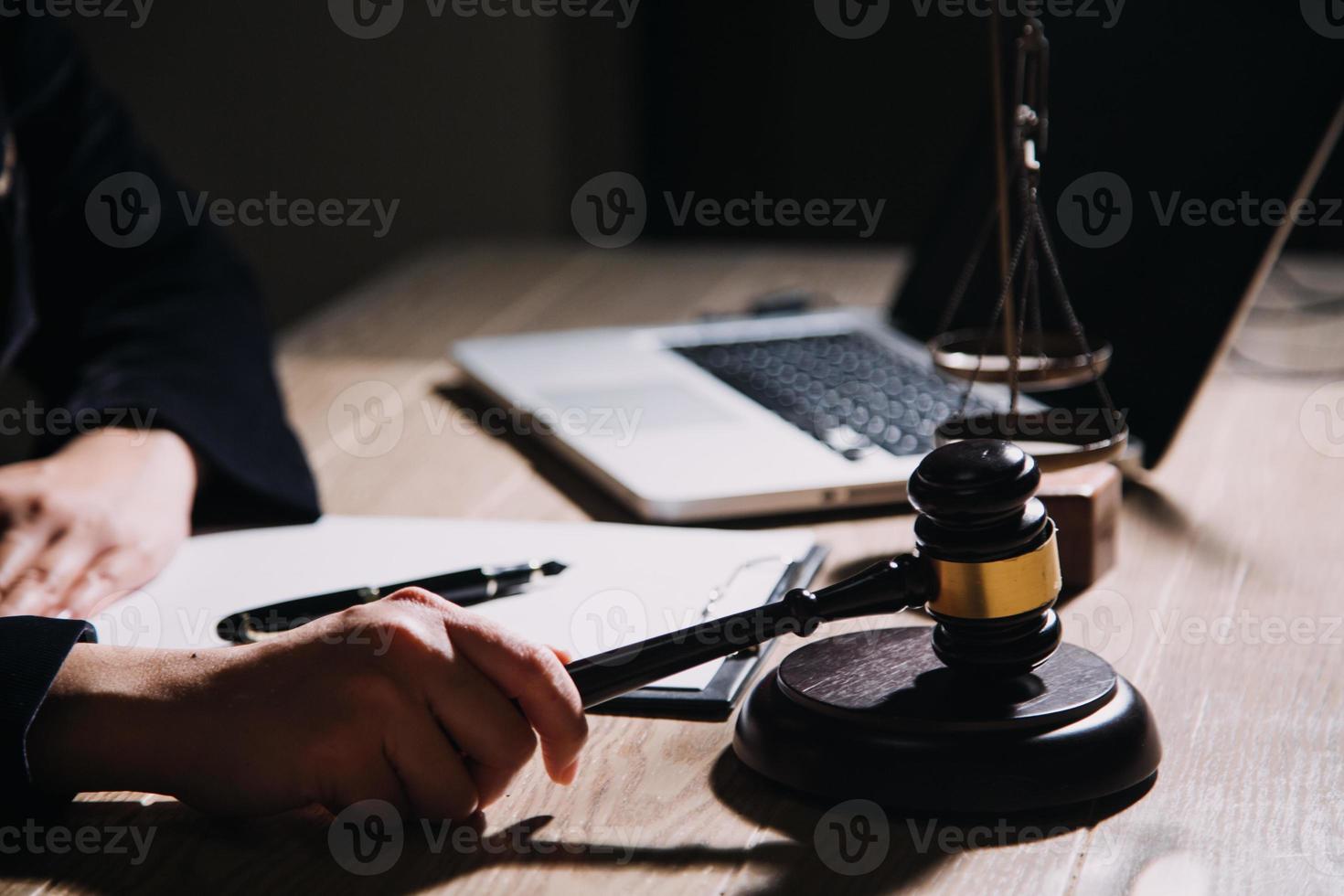 concepto de justicia y derecho. juez masculino en una sala de audiencias con el mazo, trabajando con computadora y teclado de acoplamiento, anteojos, en la mesa a la luz de la mañana foto