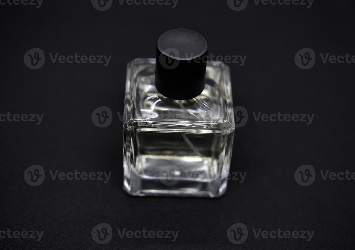 A glass perfume bottle on a black background. A bottle of perfume in close-up. Perfumery. photo