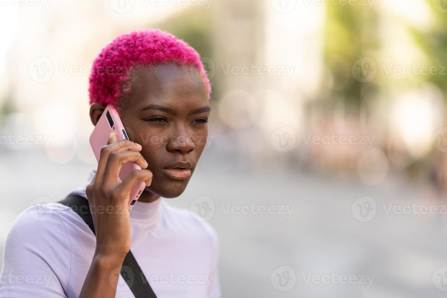 Afro woman with a distrustful expression talking on a mobile photo