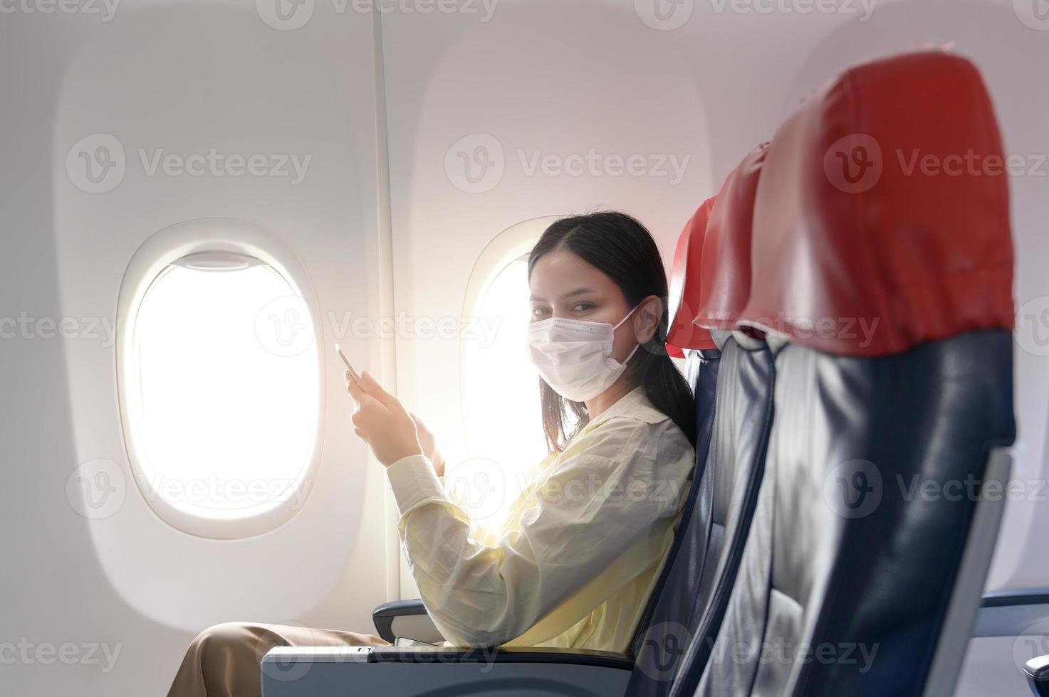 una mujer joven con mascarilla viaja en avión, nuevo viaje normal después del concepto de pandemia covid-19 foto