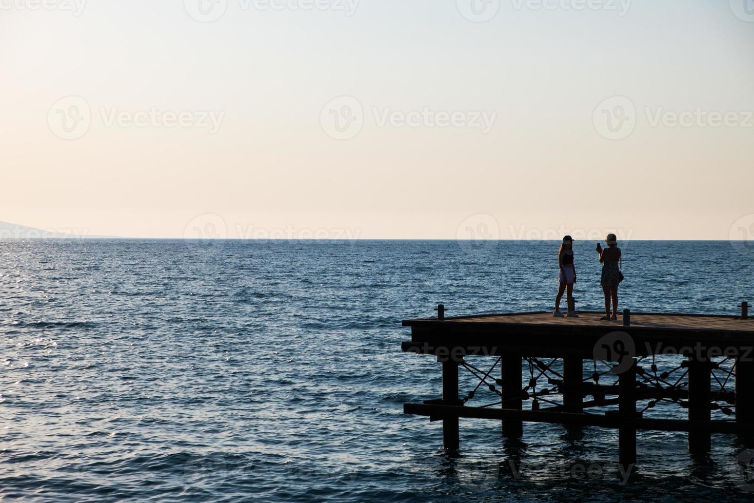 Silhouettes of people on a derelict pier photo