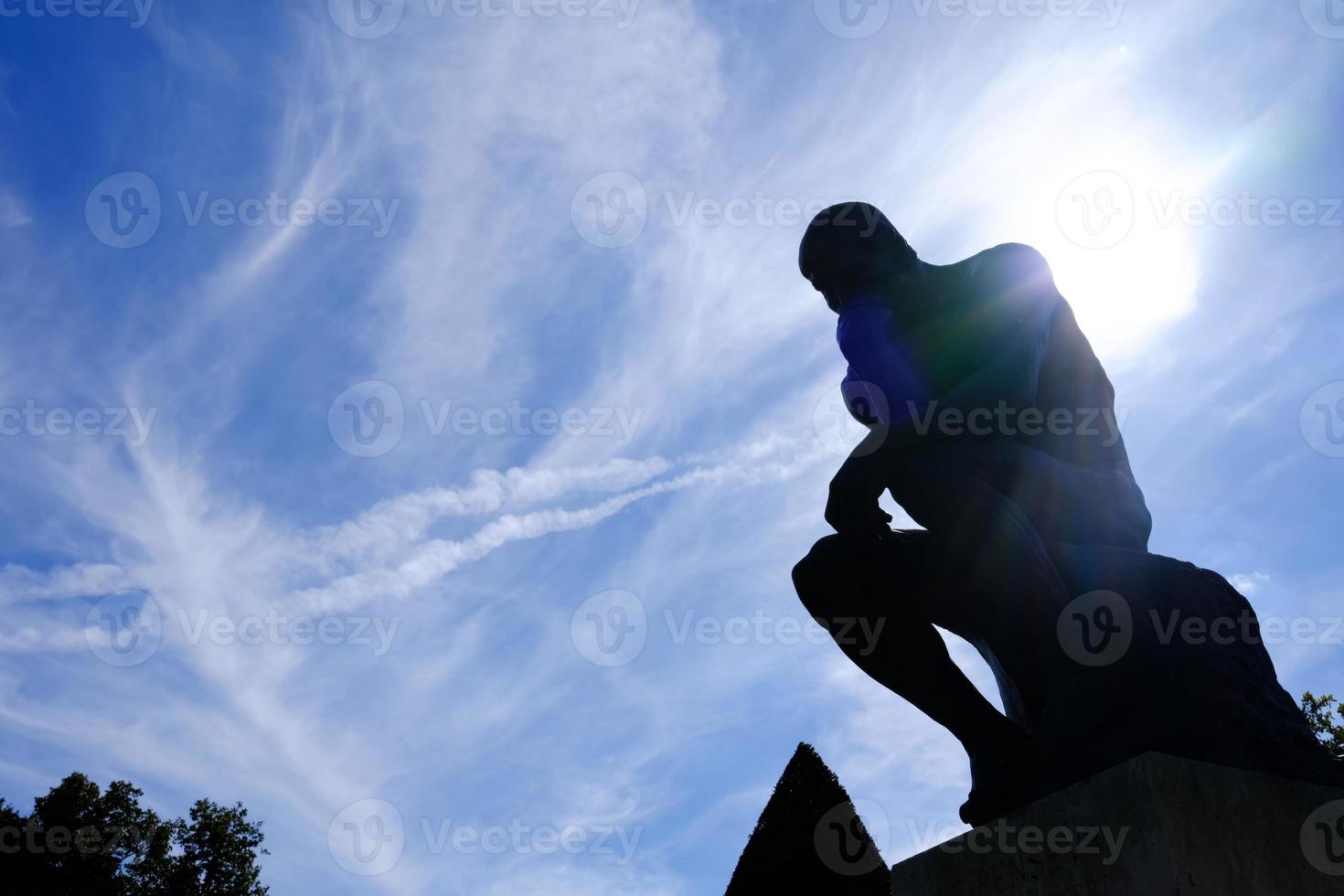 Silhouette Thinker Statue with Fare Light and Blue Sky Background in front of Rodin Museum, Paris France. photo