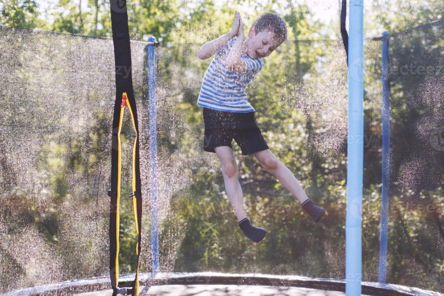 boy jumping on trampoline. the child plays on a trampoline outdoor photo